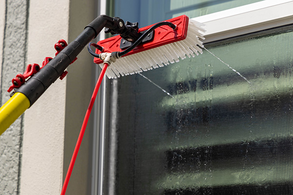 red squeegee brush being used to wash windows